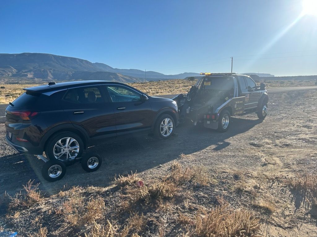 A car is being towed by a tow truck in the desert.