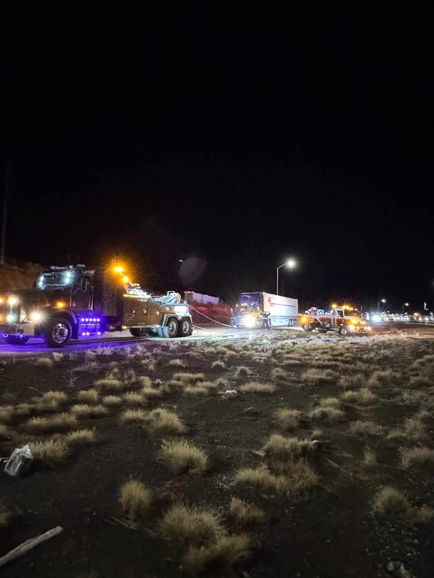 A row of trucks are parked on the side of the road at night.