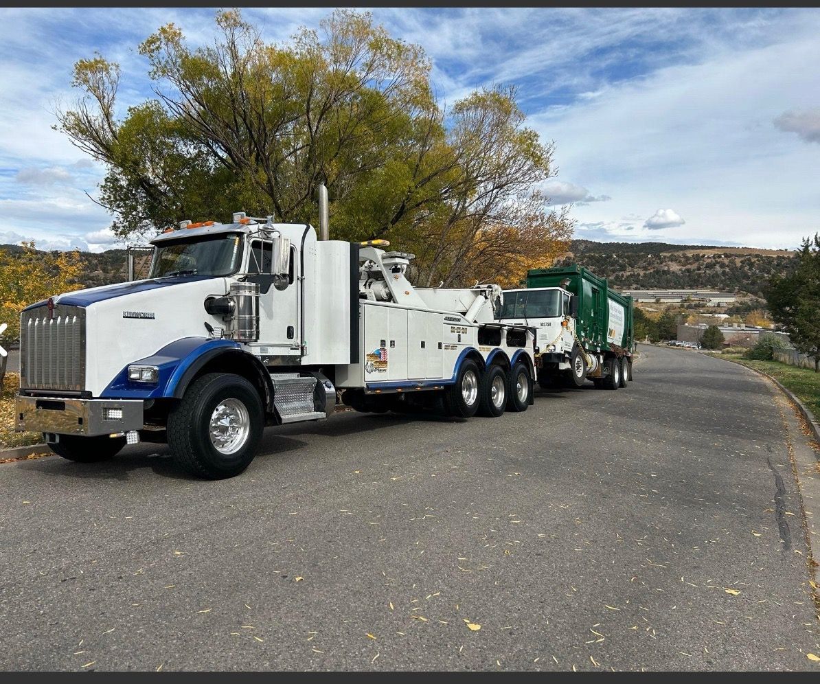 Two tow trucks are parked on the side of a road.