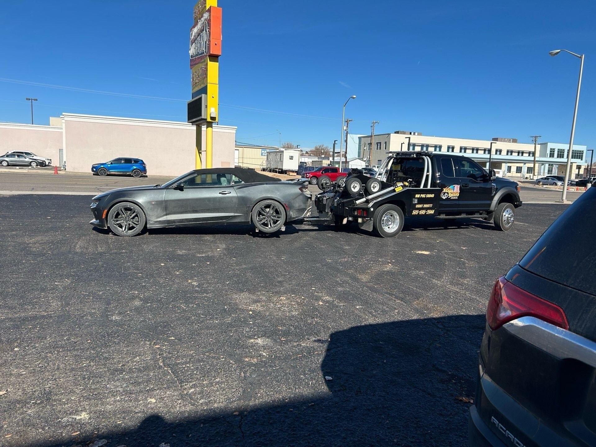 A car is being towed by a tow truck in a parking lot.