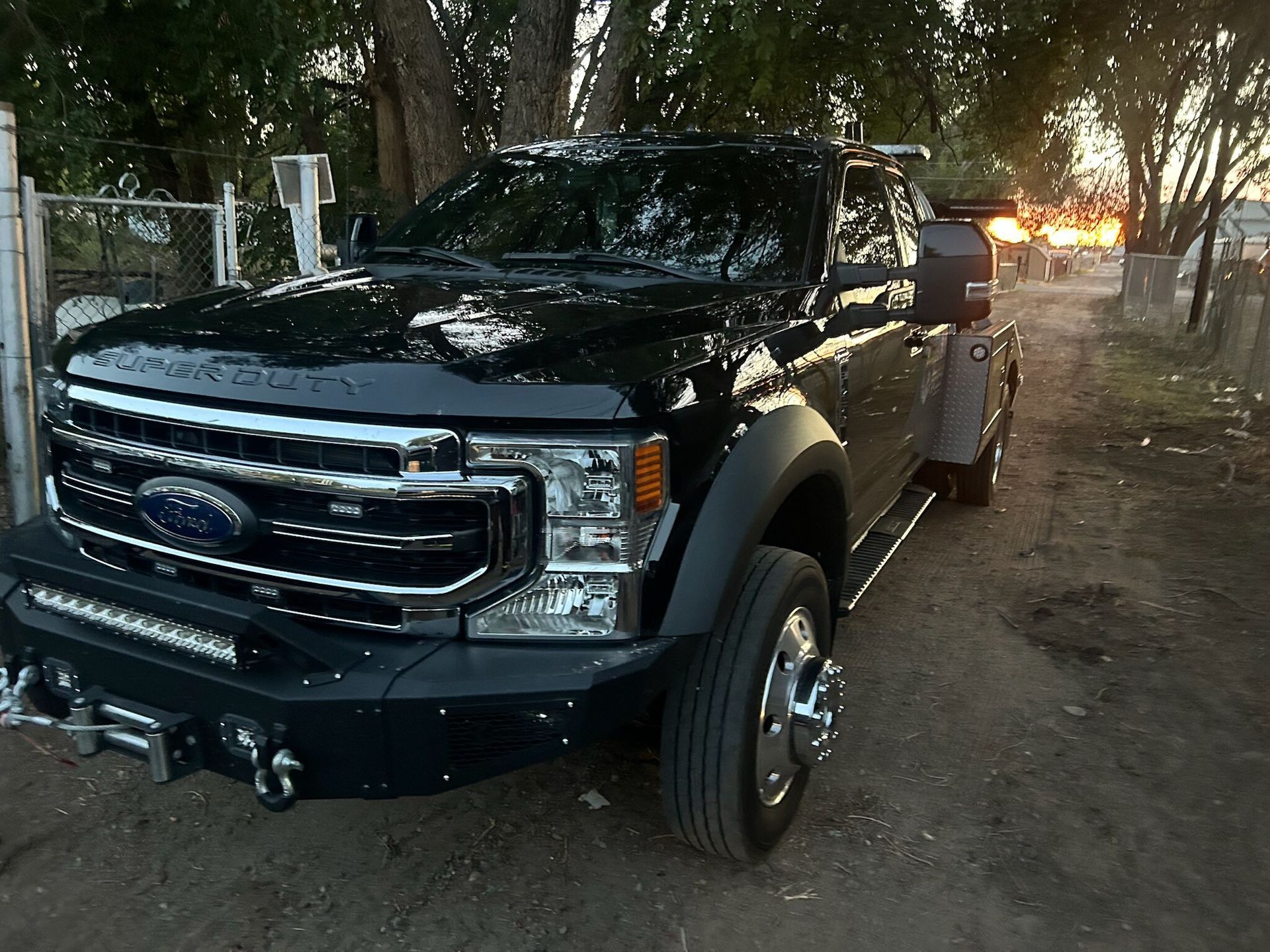 A black ford truck is parked on a dirt road