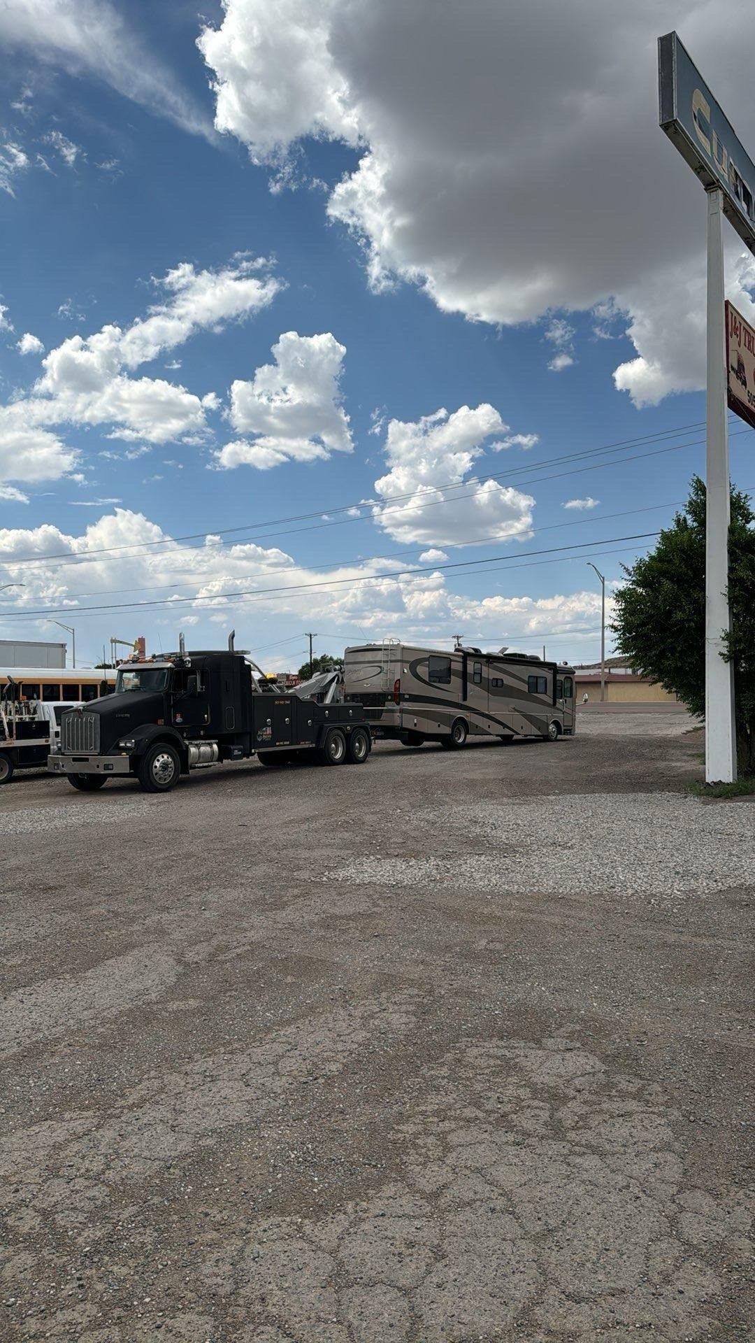 A truck is towing a trailer in a gravel lot.