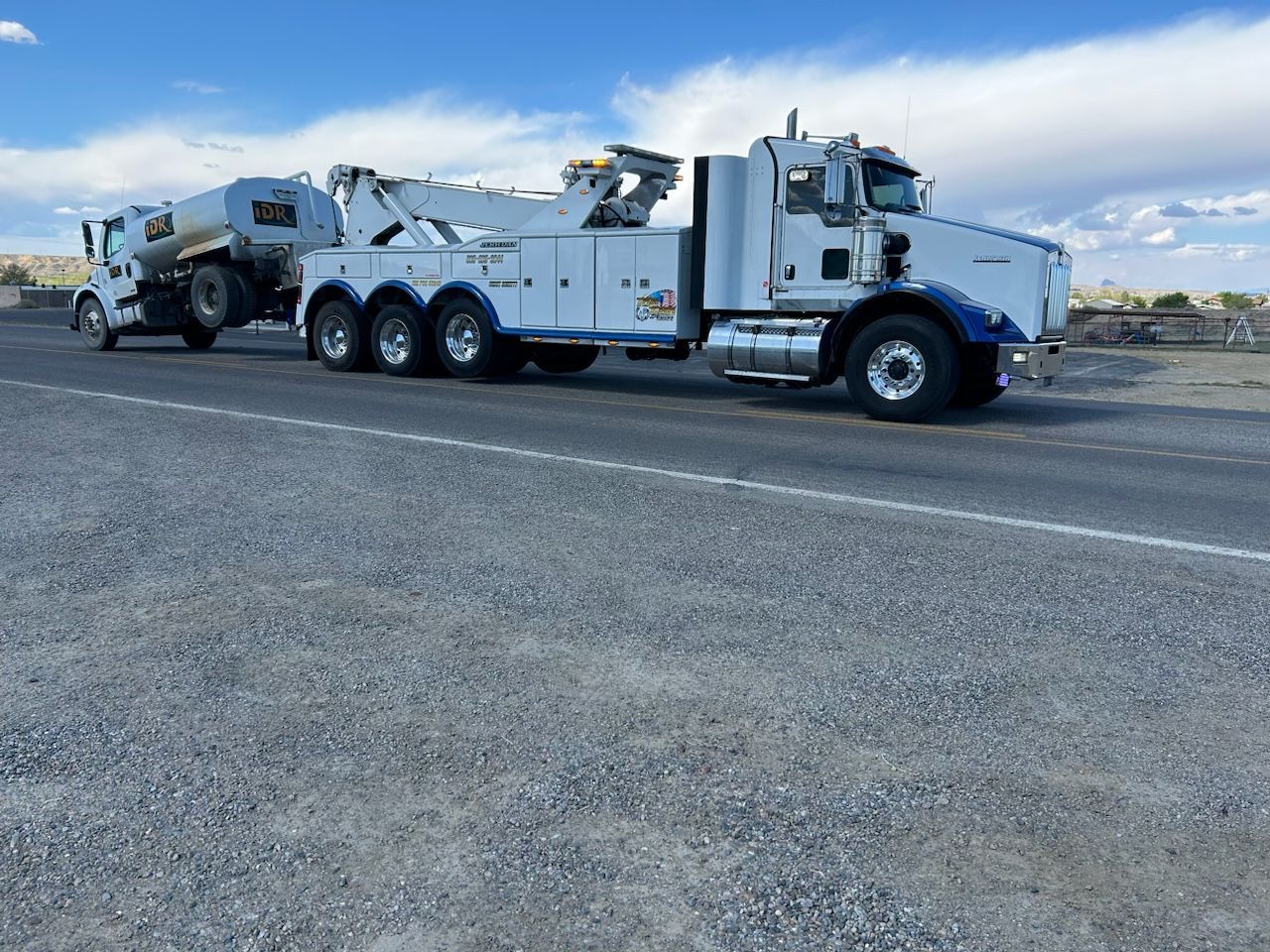 A white tow truck is parked on the side of the road