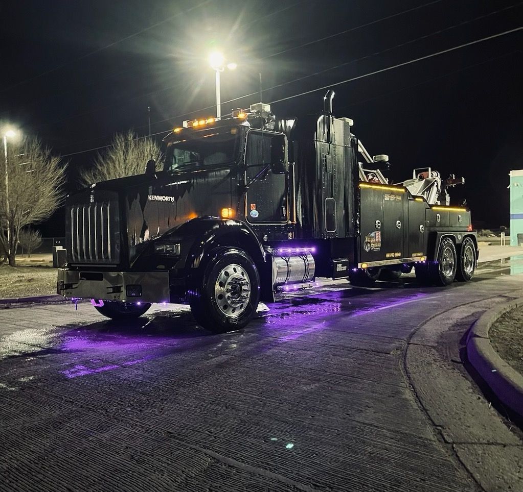 A tow truck is parked on the side of the road at night