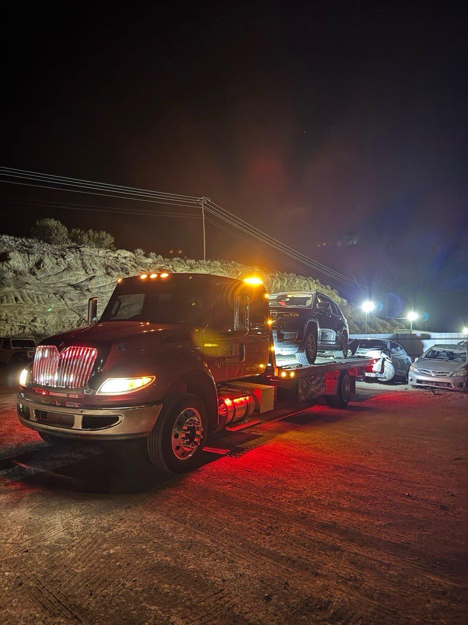 A tow truck is parked in a parking lot at night.
