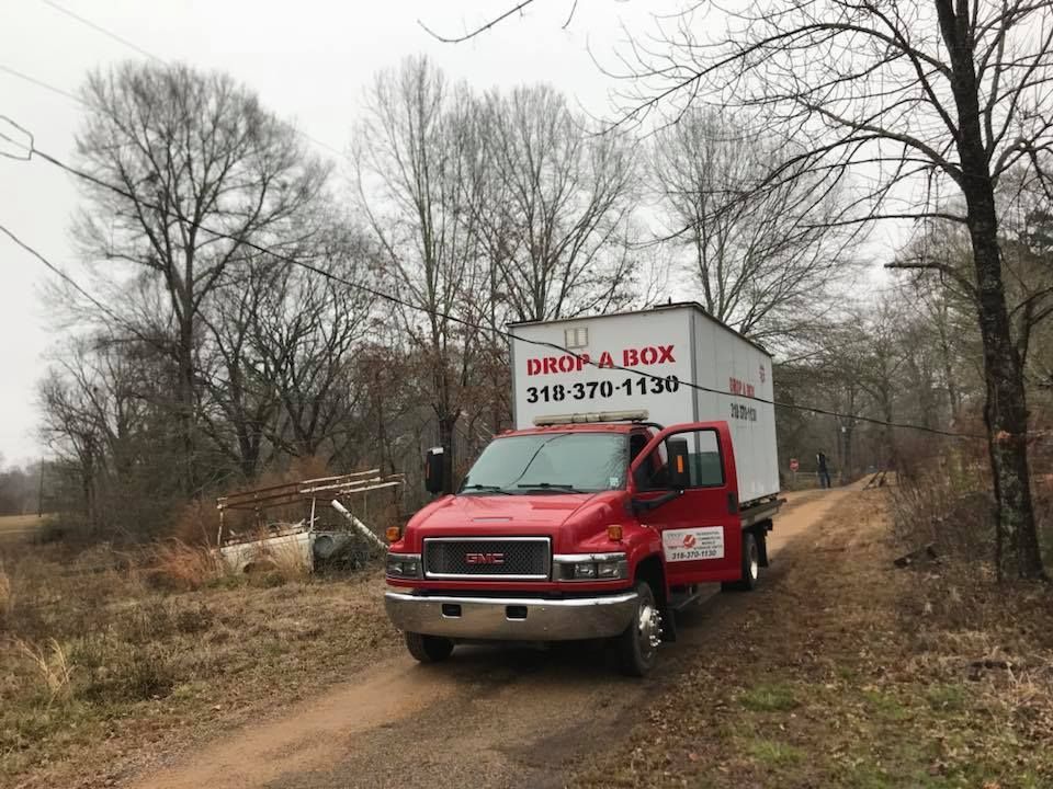 A red moving truck is parked on the side of a dirt road.