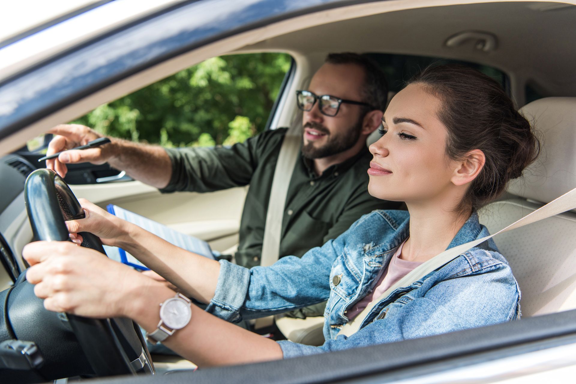 Cheerful student and driving instructor in a car taking a test.