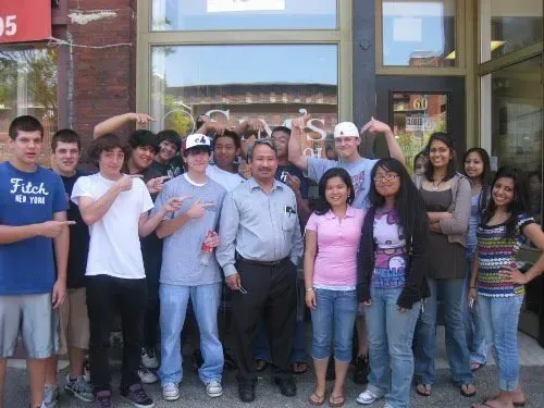 A group of people posing in front of a store that says fitch on it