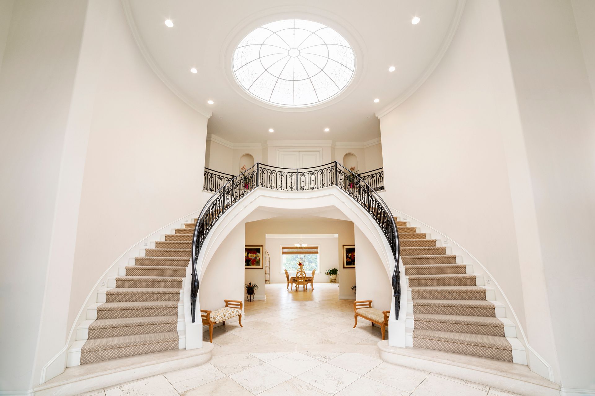 A large white hallway with stairs and a dome in the ceiling.