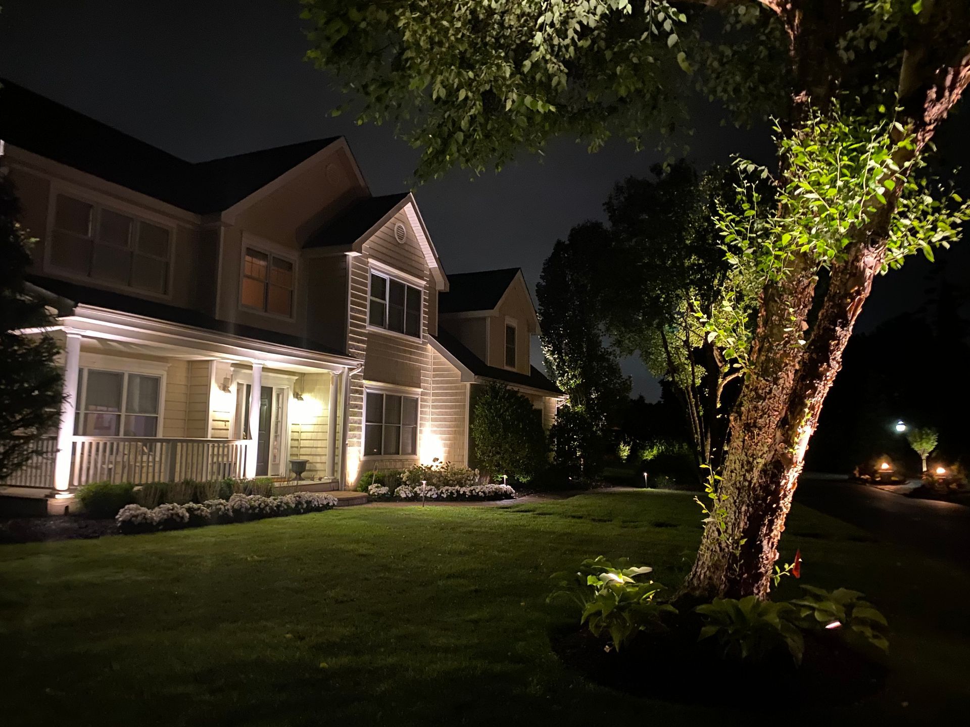 A house is lit up at night with trees in front of it