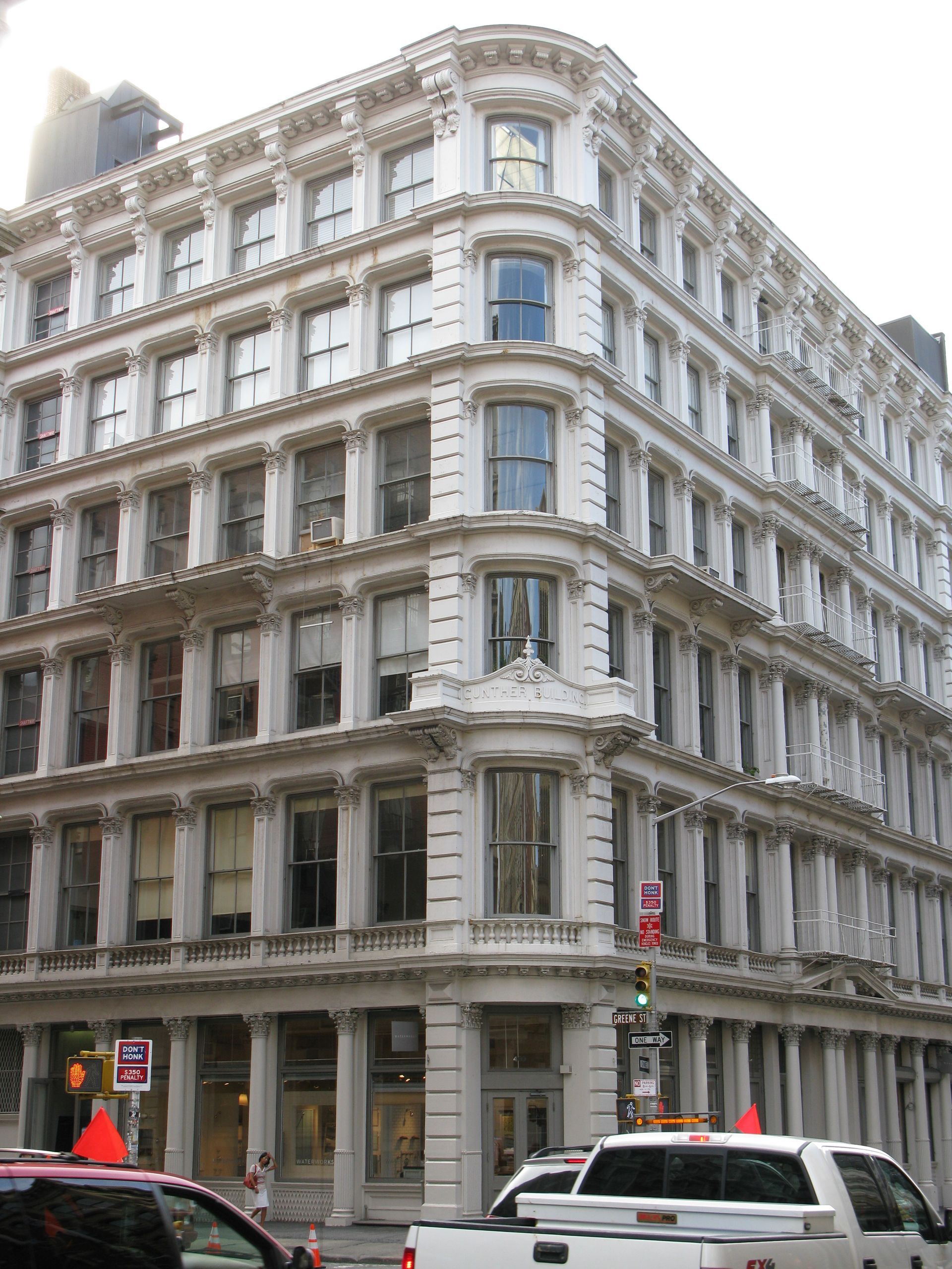 Storefront with copper-colored trim and glass windows; plants and bench in front, mannequins inside.