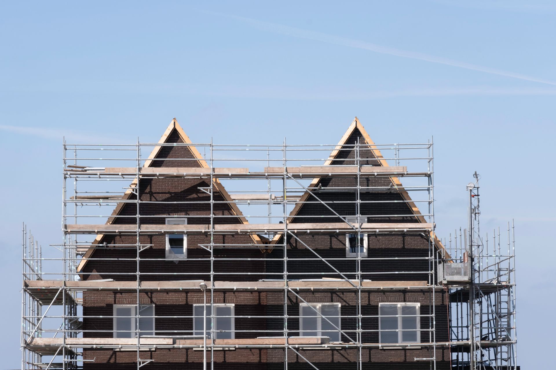 Scaffolding pile platform against two identical newly built terraced houses on a construction site. Scaffolding pile platform against two identical newly built terraced houses on a construction site.