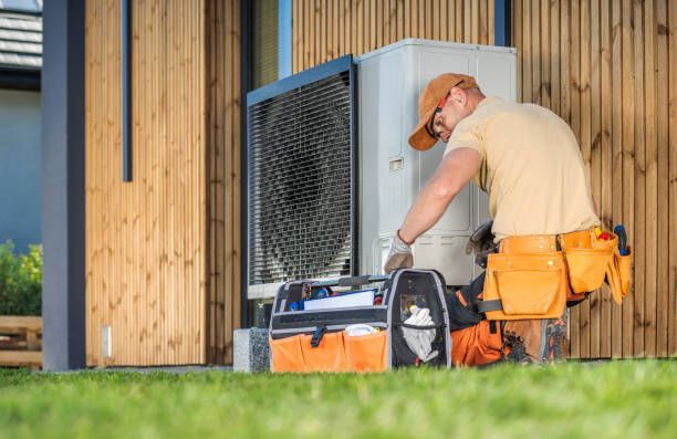 HVAC technician servicing a modern heat pump unit outside a residential home 