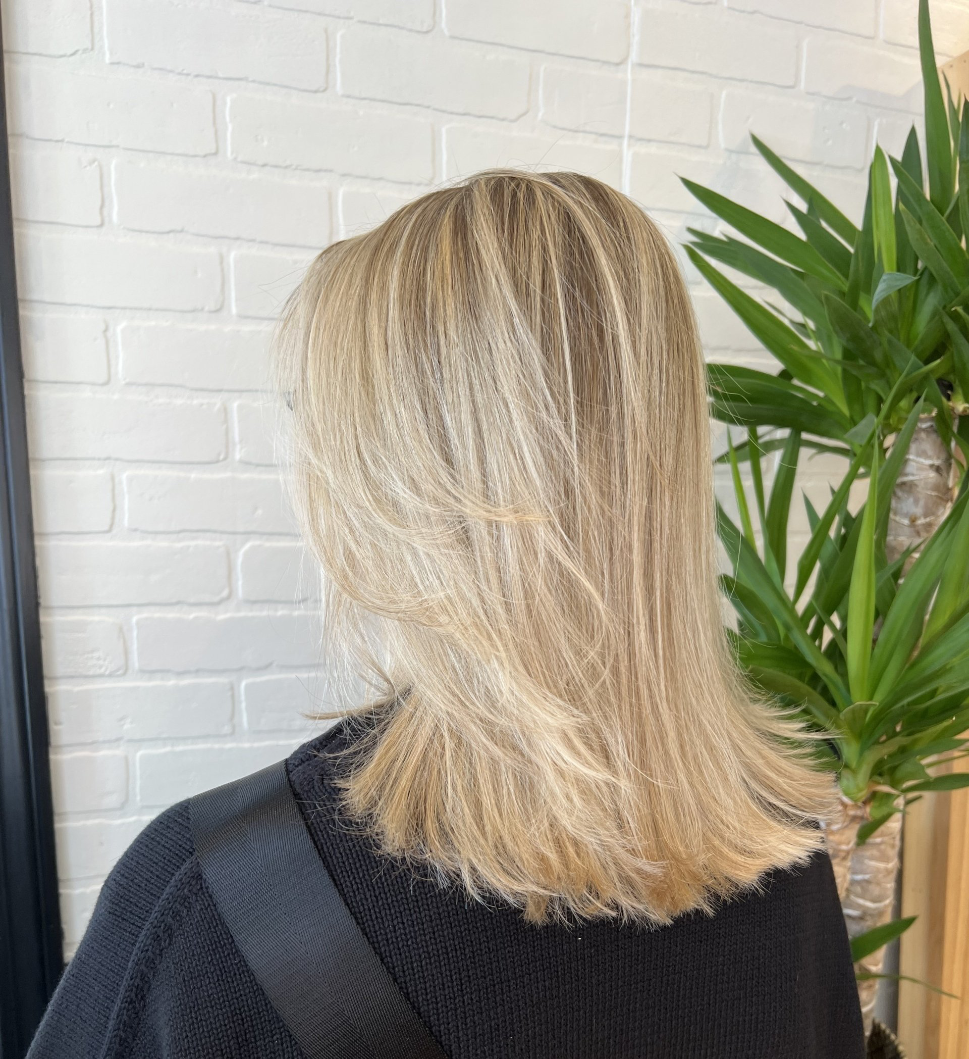A woman with blonde hair is wearing a black sweater.