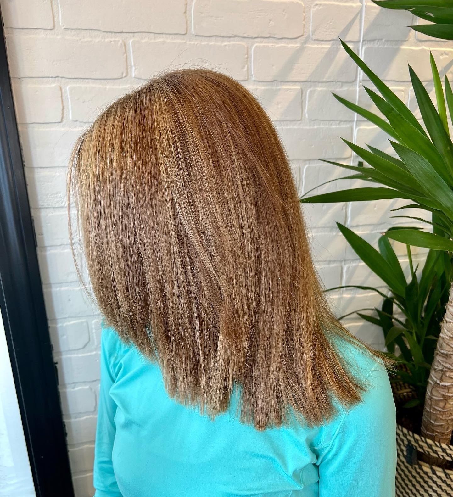 A woman with long blonde hair is wearing a blue shirt.