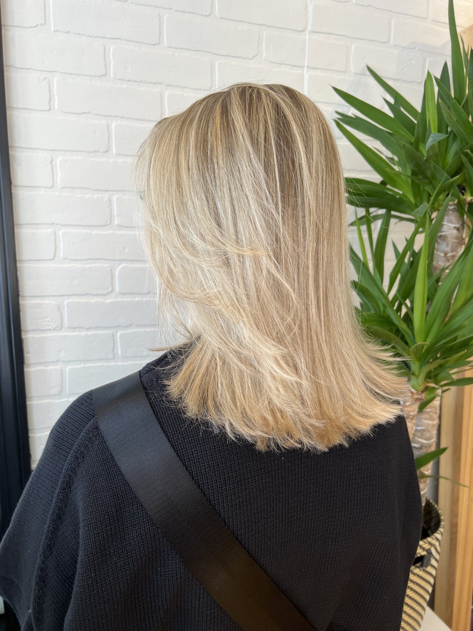 A woman with blonde hair is wearing a black sweater.