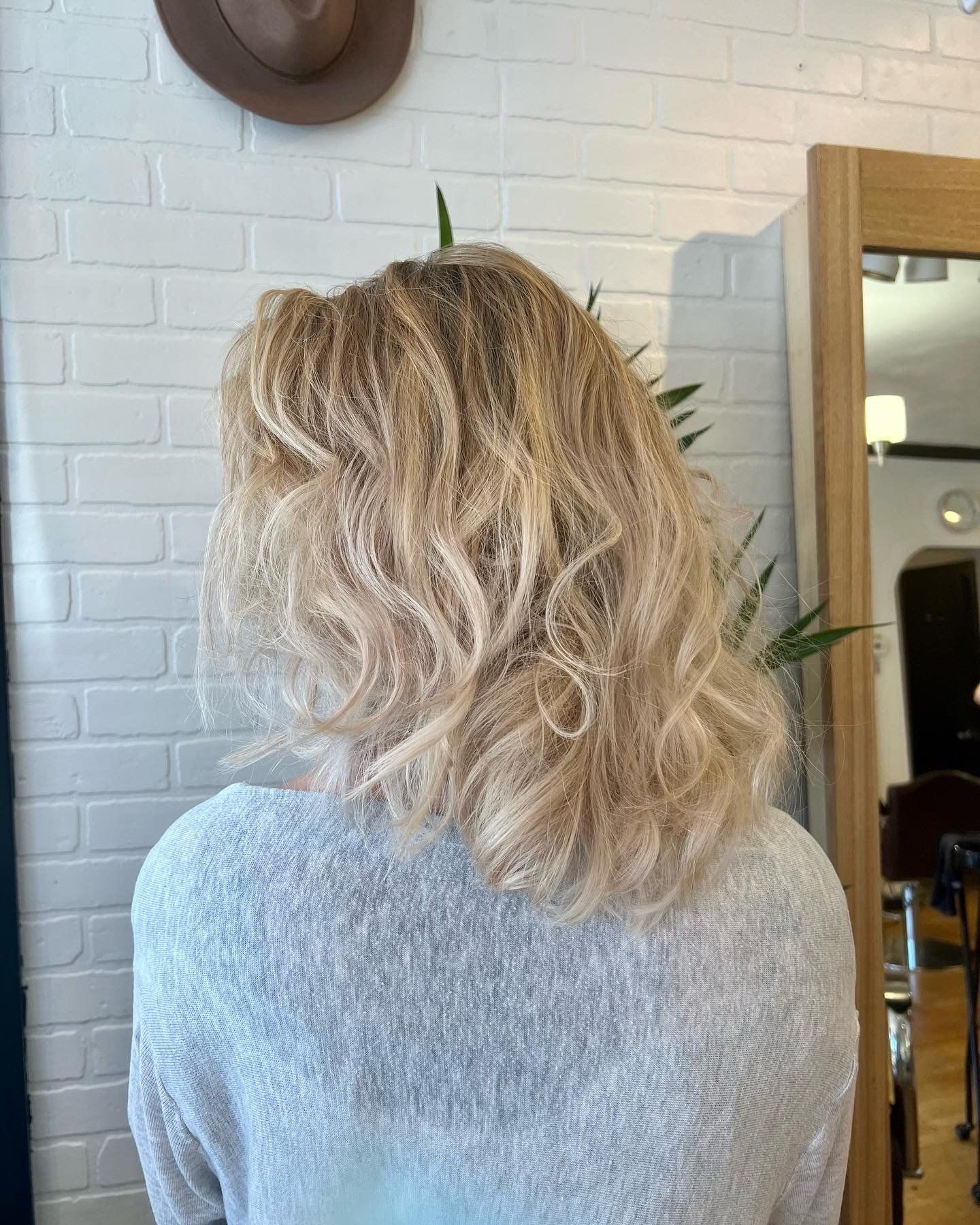 A woman with blonde hair is standing in front of a mirror.