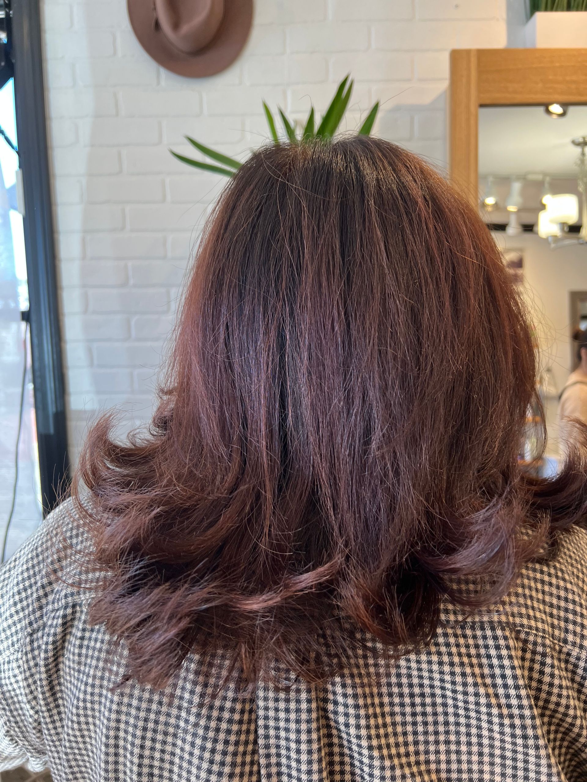 A woman with long brown hair is standing in front of a mirror.