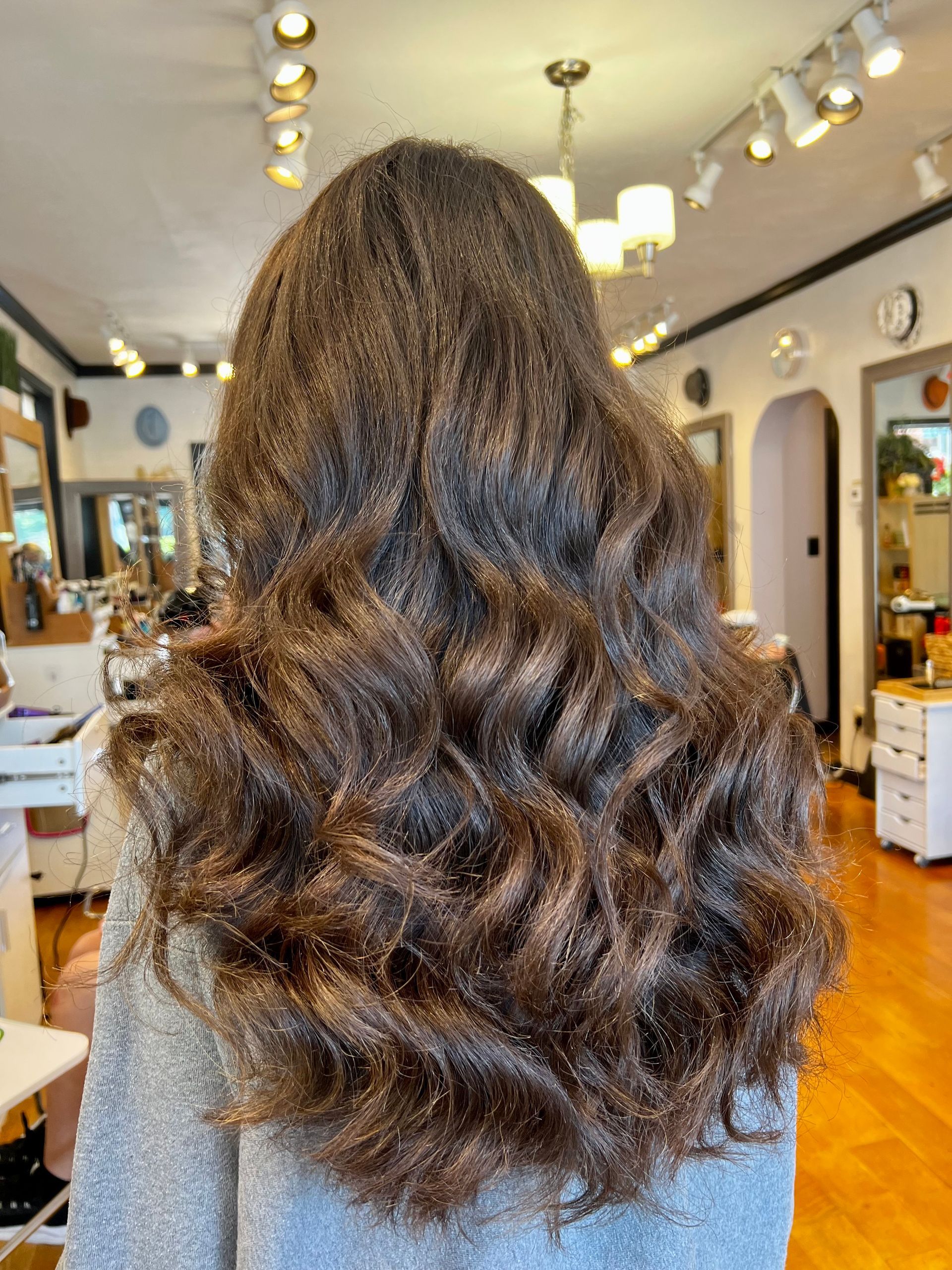 A woman with long curly hair is sitting in a salon.
