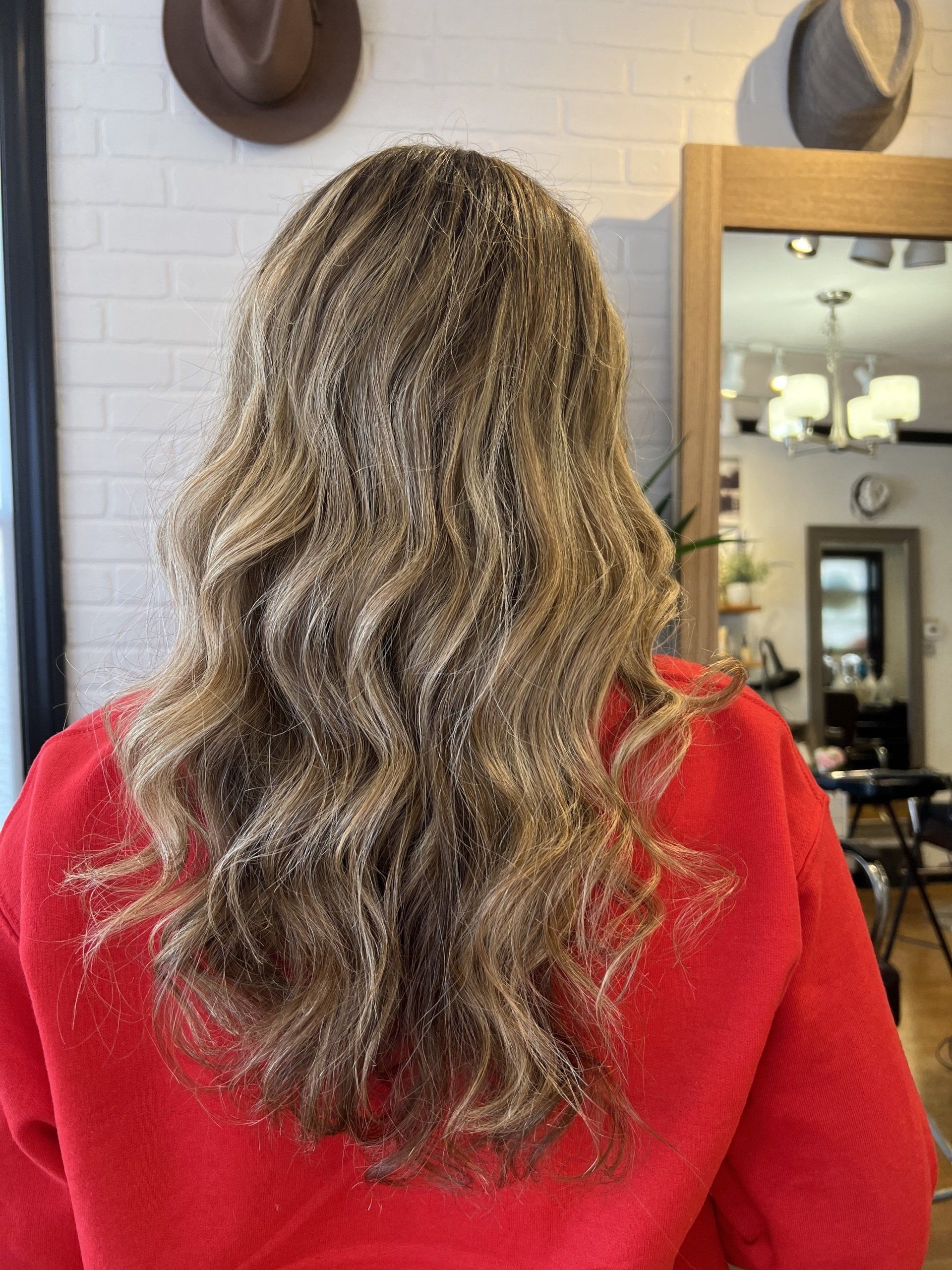 The back of a woman 's head with long blonde hair and a red jacket.
