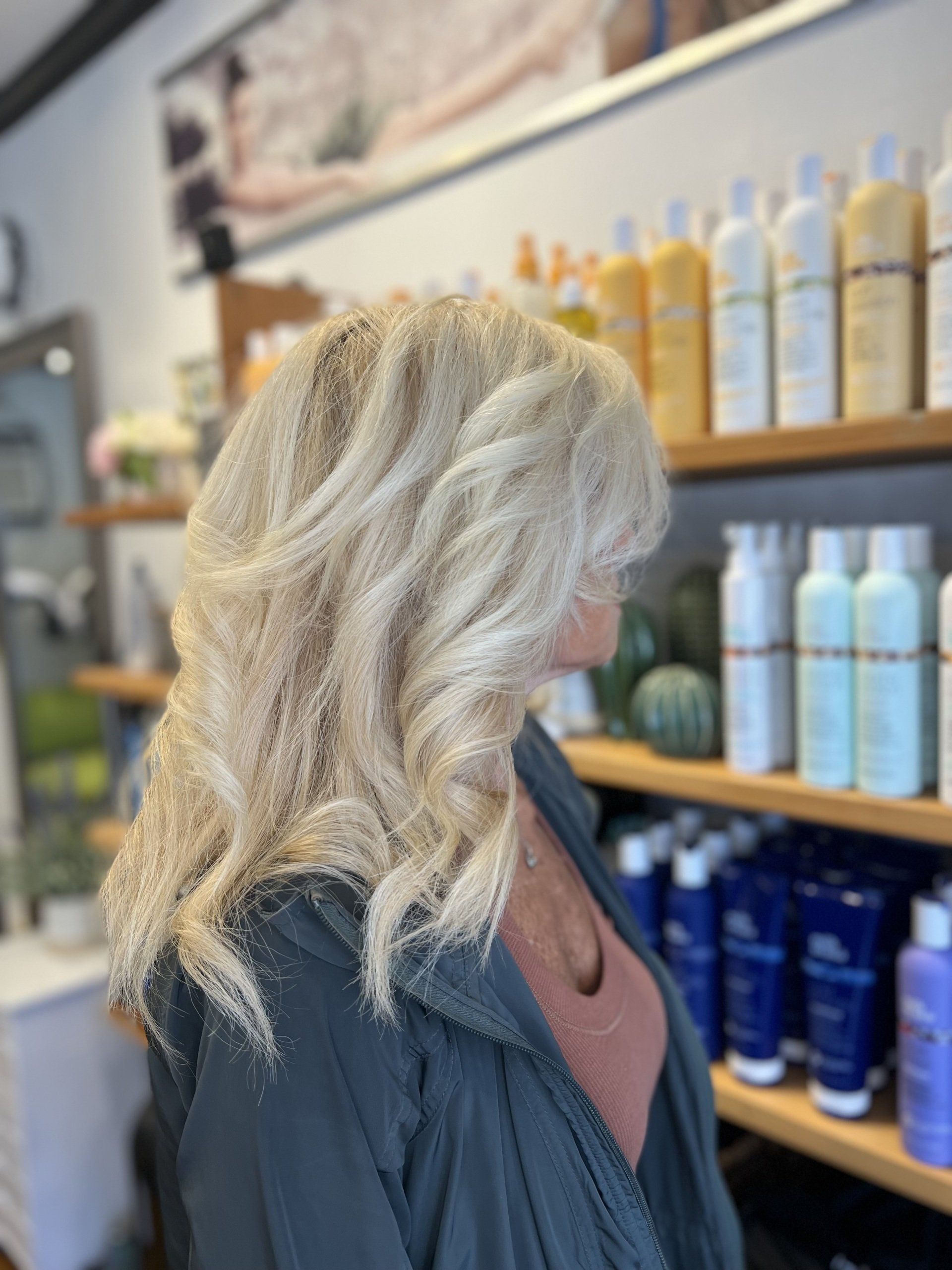 A woman is standing in front of a shelf full of hair products