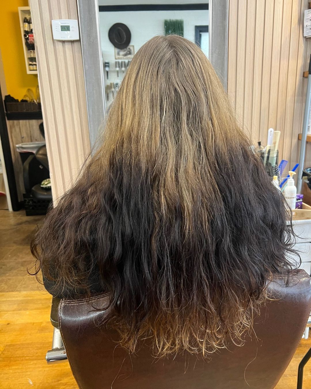 A woman with long hair is sitting in a chair in a salon.