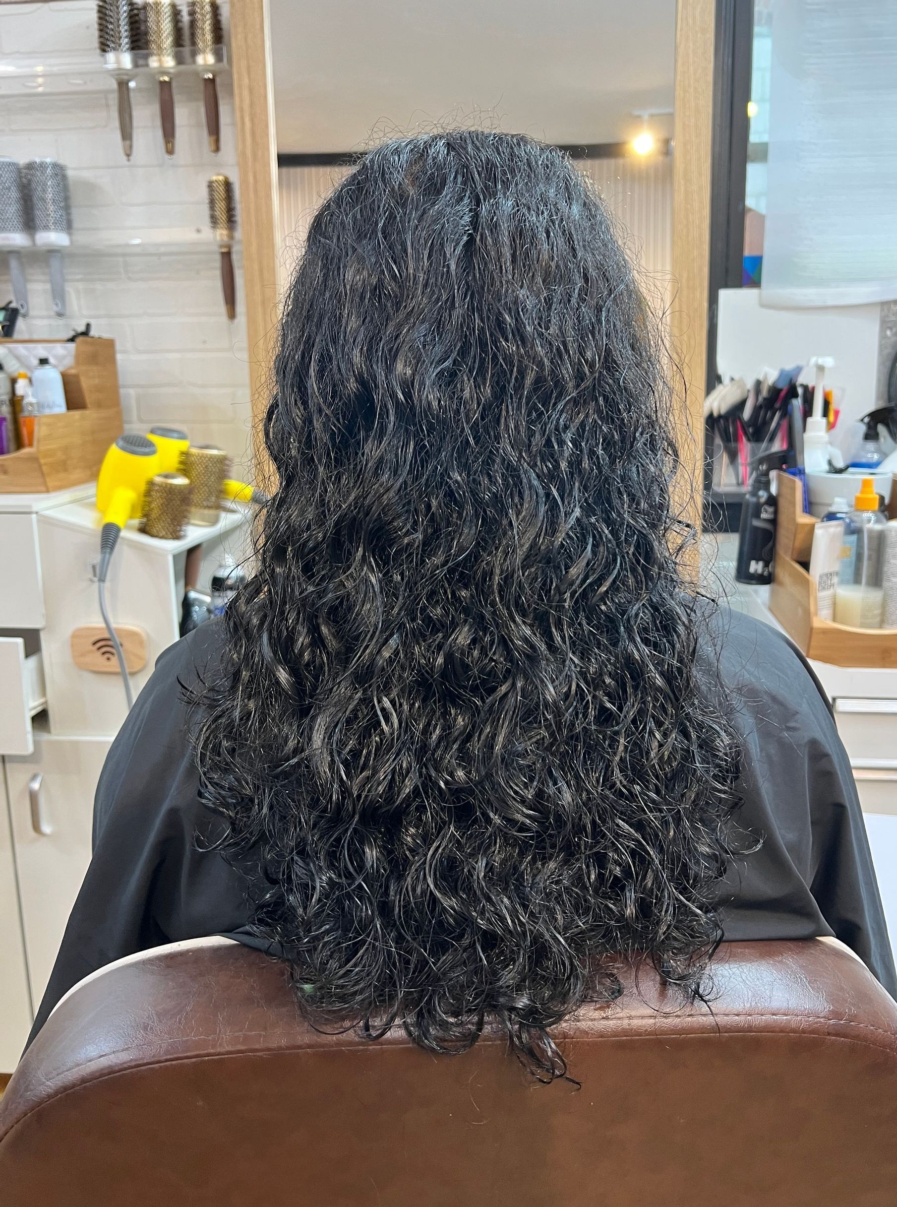 A woman with curly hair is sitting in a chair in a salon.