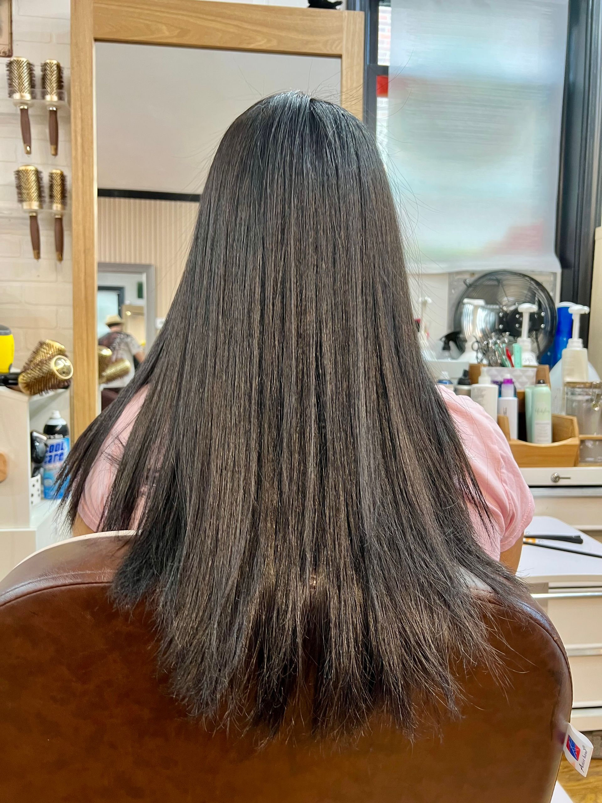 A woman with long hair is sitting in a chair in front of a mirror.