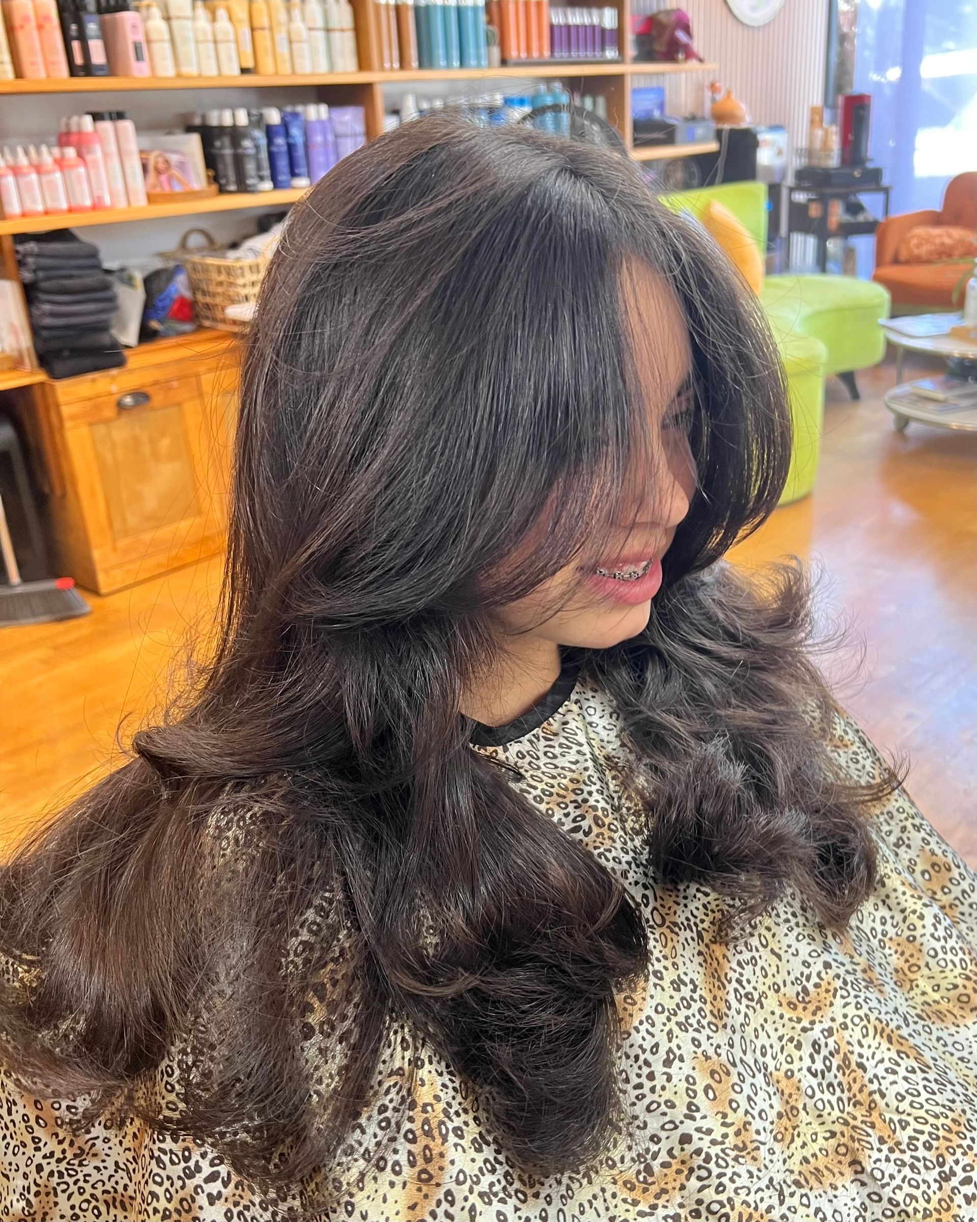 A woman with long hair is sitting in a chair in a salon.