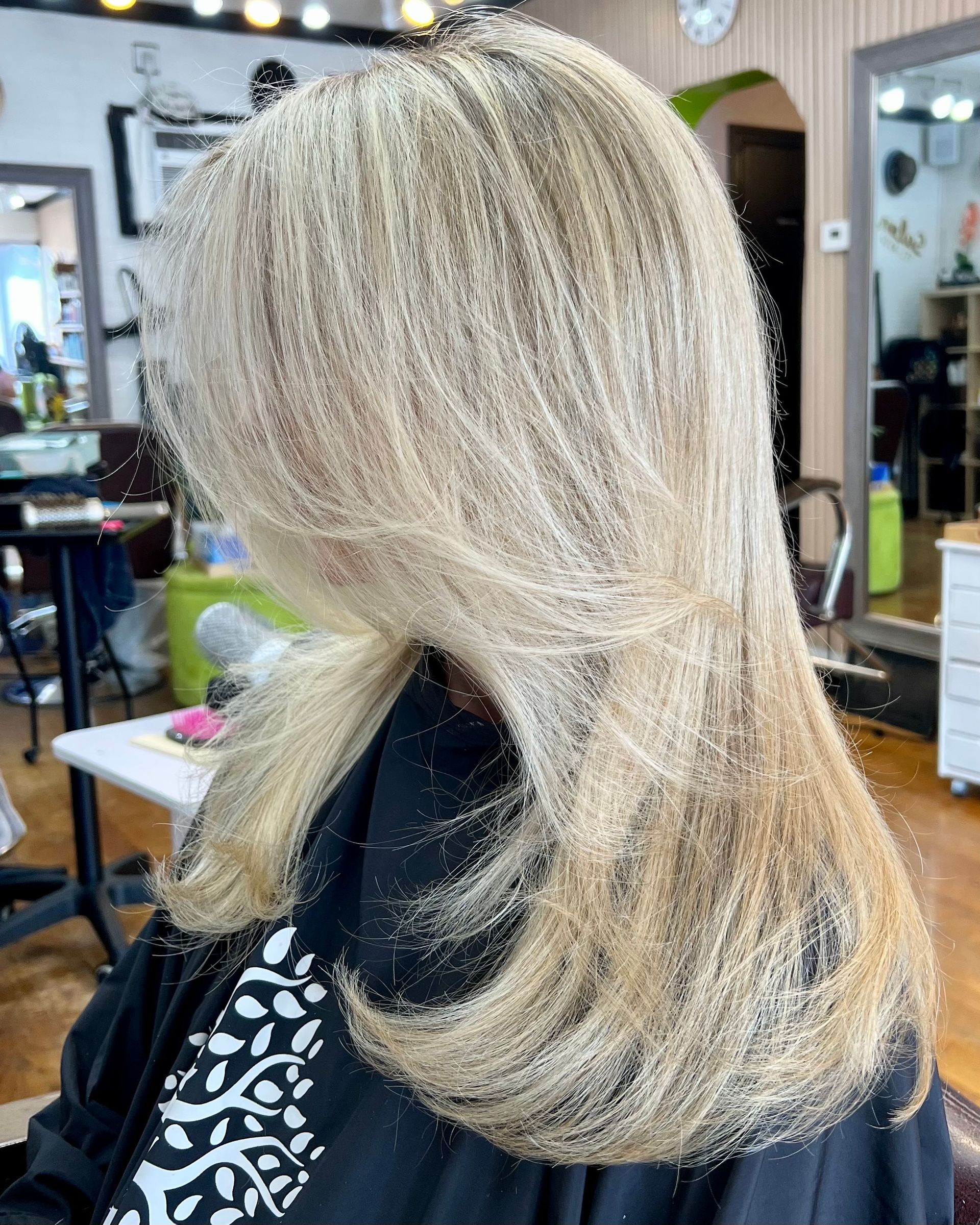 A woman with blonde hair is sitting in a chair in a salon.