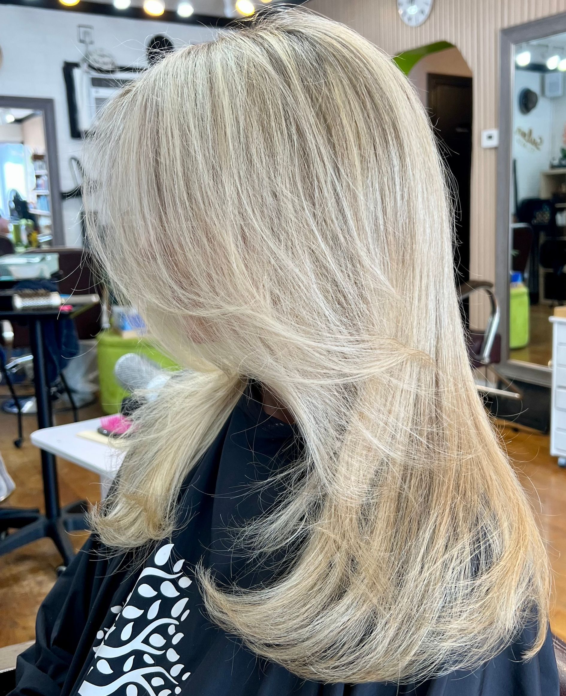 A woman with blonde hair is getting her hair cut in a salon.