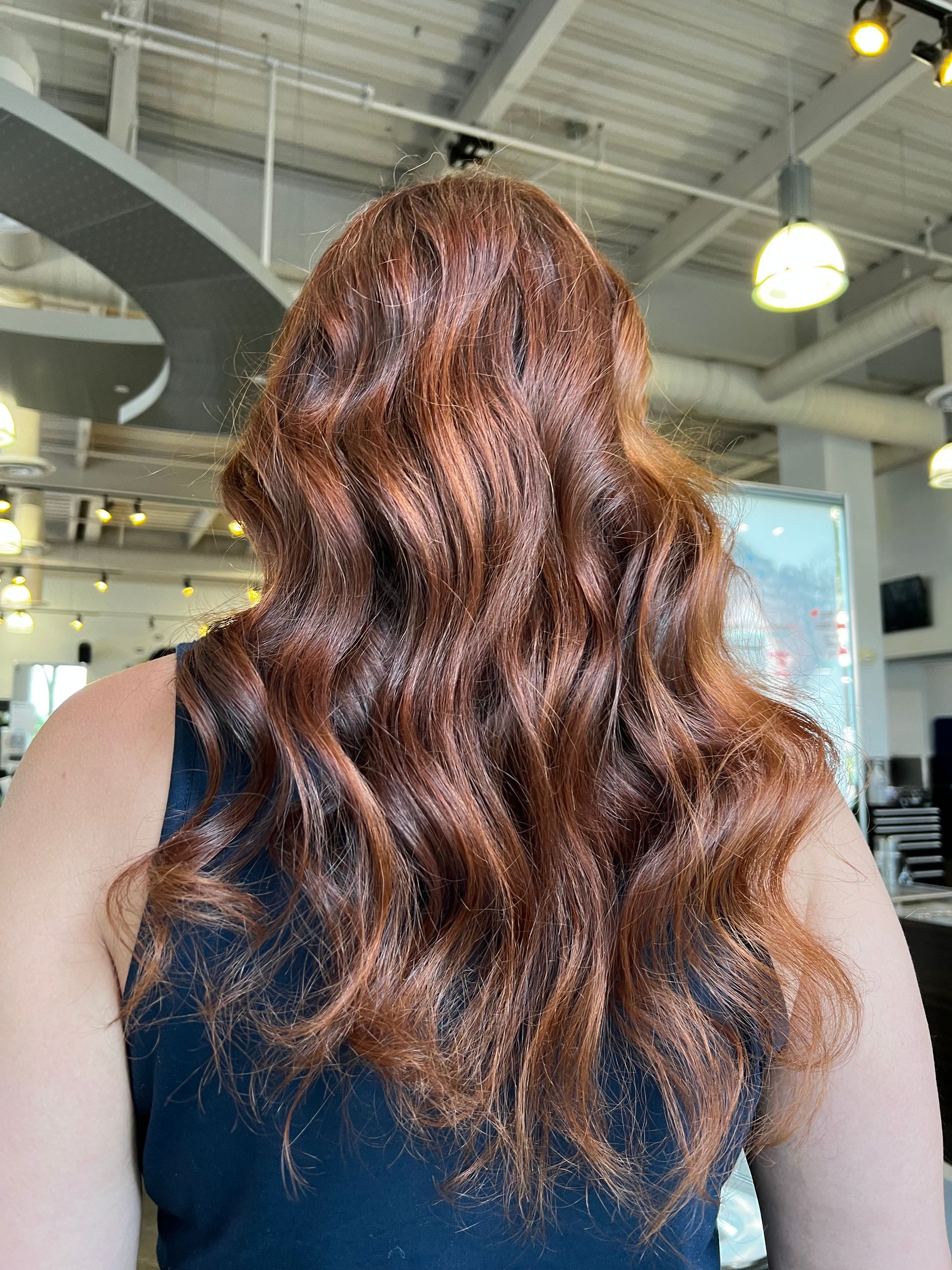 A woman with long red hair is wearing a black tank top.