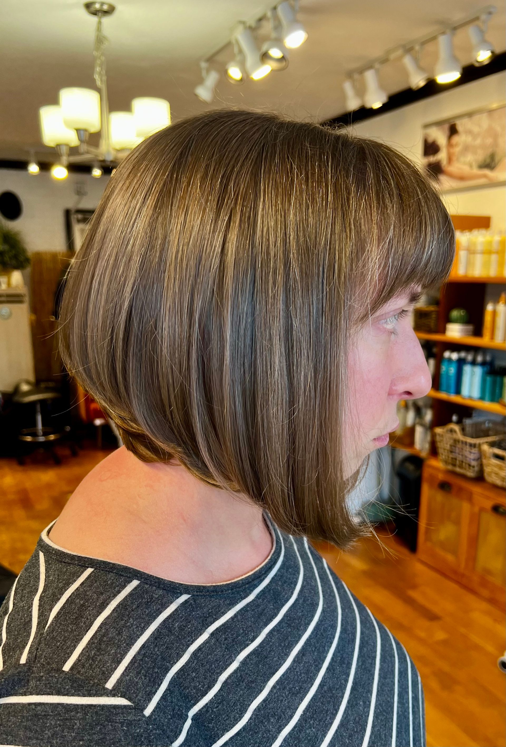 A woman with short hair is wearing a striped shirt in a salon.