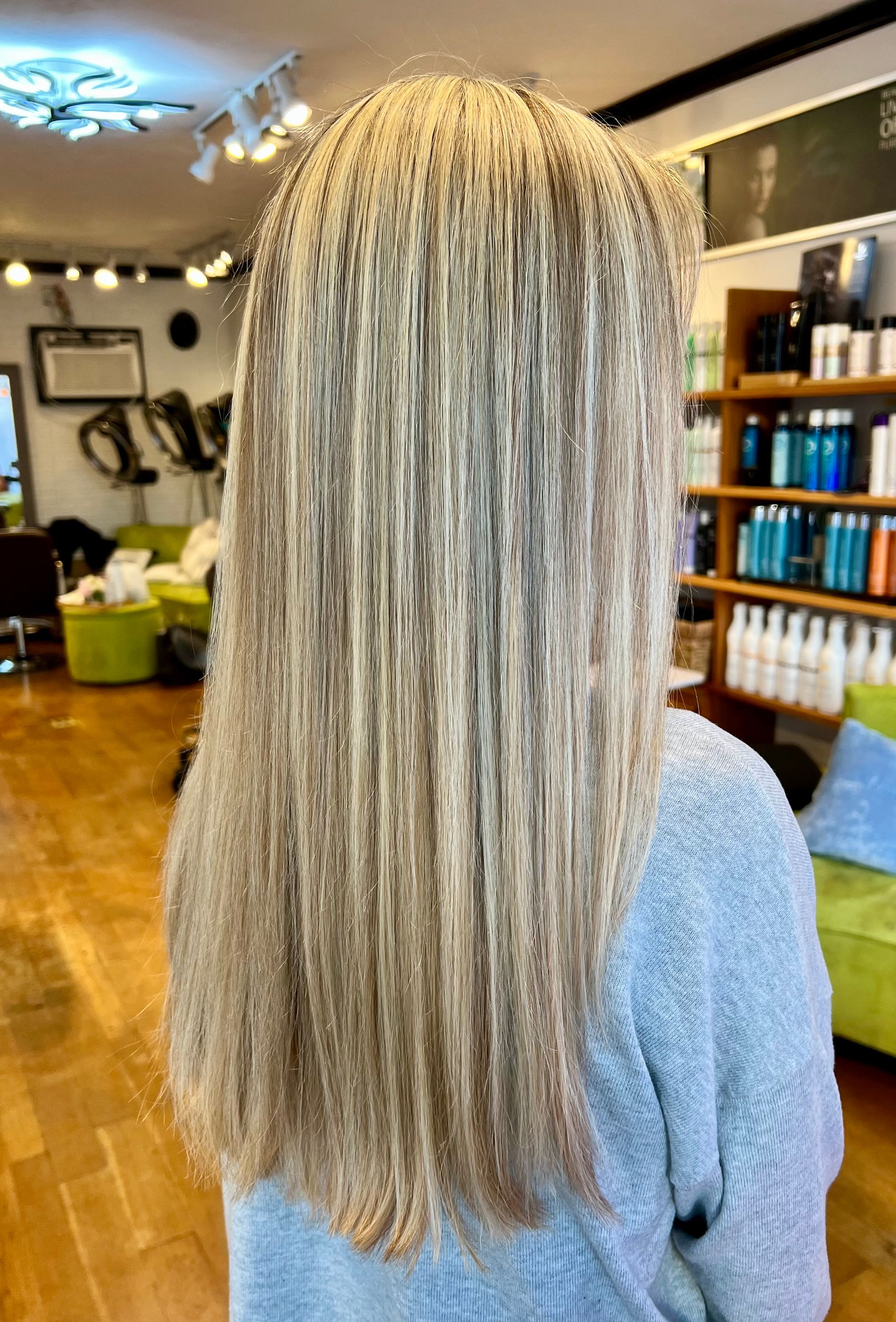 A woman with long blonde hair is standing in a salon.