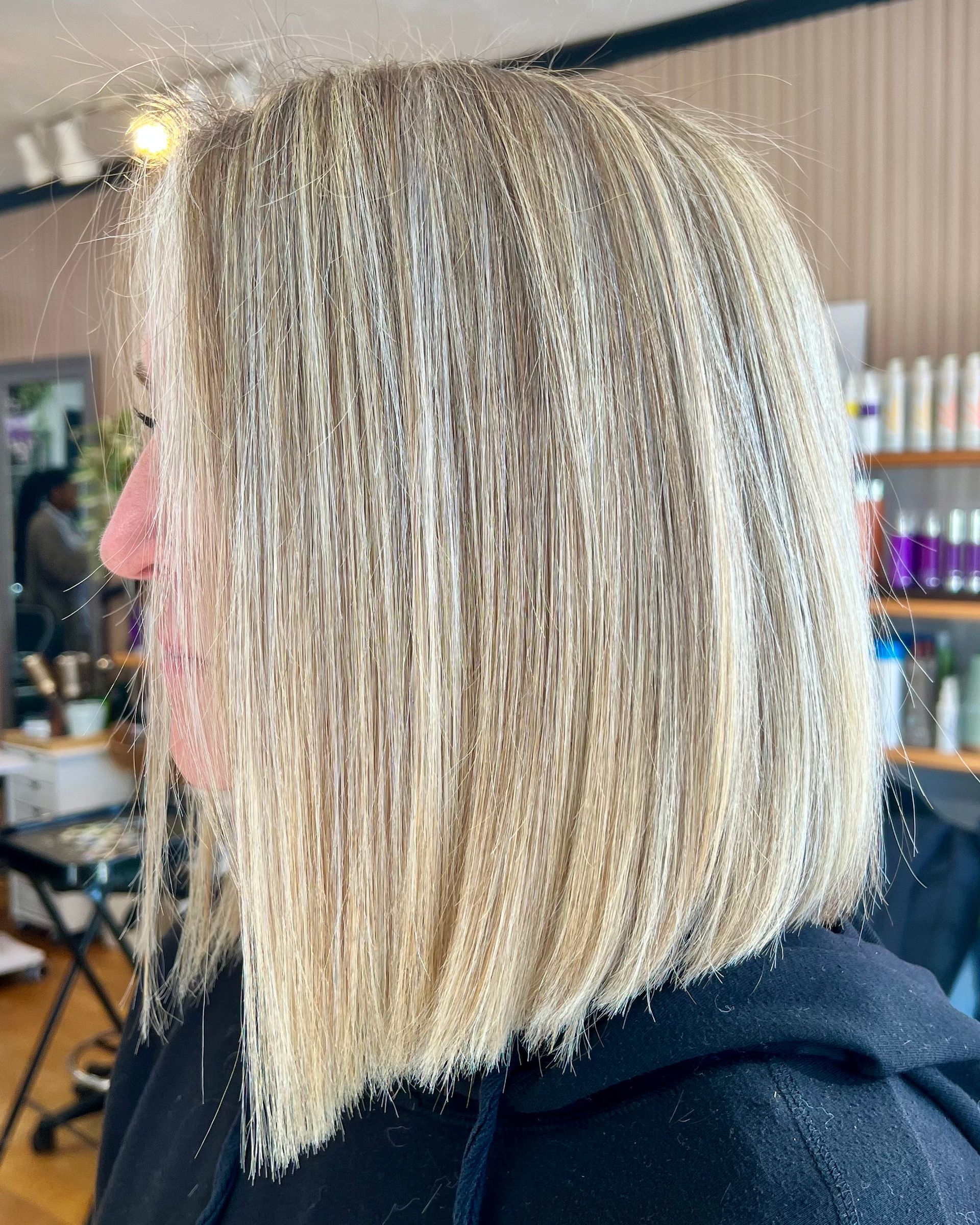 A woman with blonde hair is sitting in a chair in a salon.