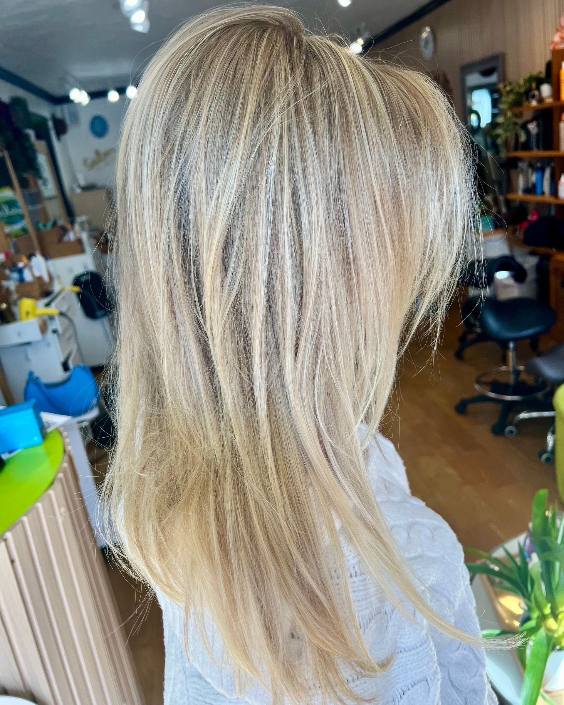 A woman with long blonde hair is sitting in a salon.