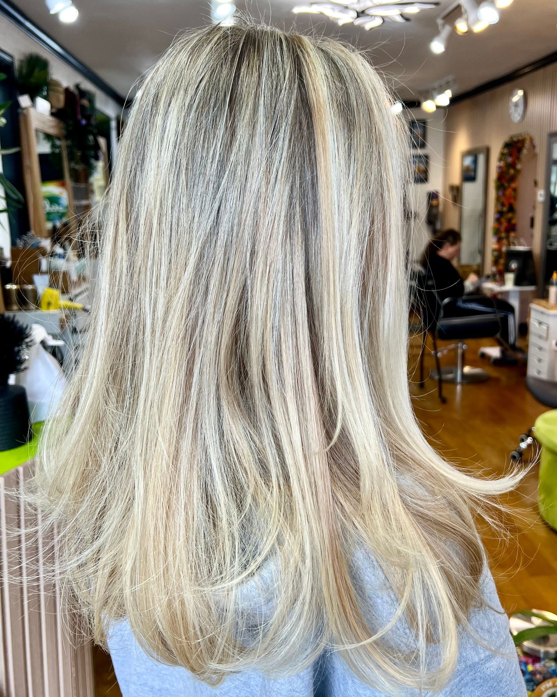 A woman with long blonde hair is sitting in a salon.