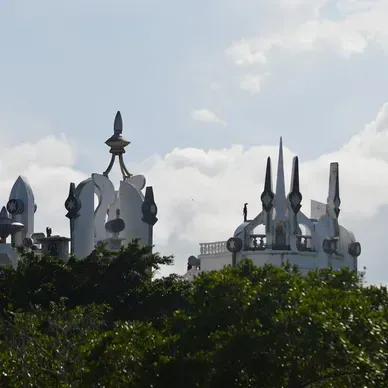 A white building with a tower on top of it surrounded by trees