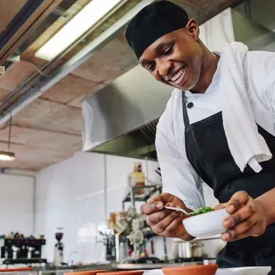 A chef is smiling while preparing food in a kitchen