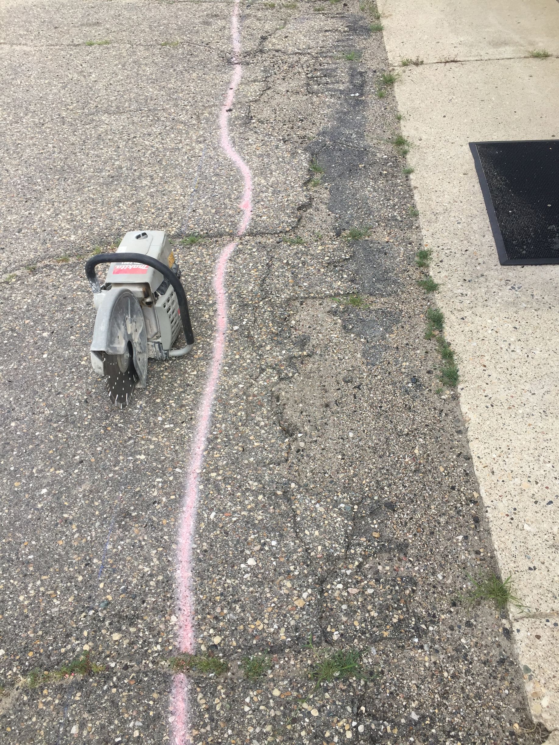 A chainsaw is sitting on the side of a road next to a chalk line.