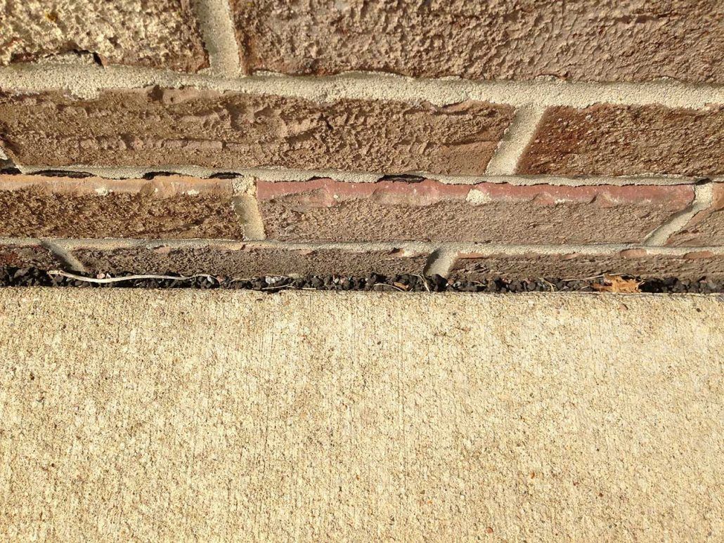 A close up of a brick wall with a concrete border.