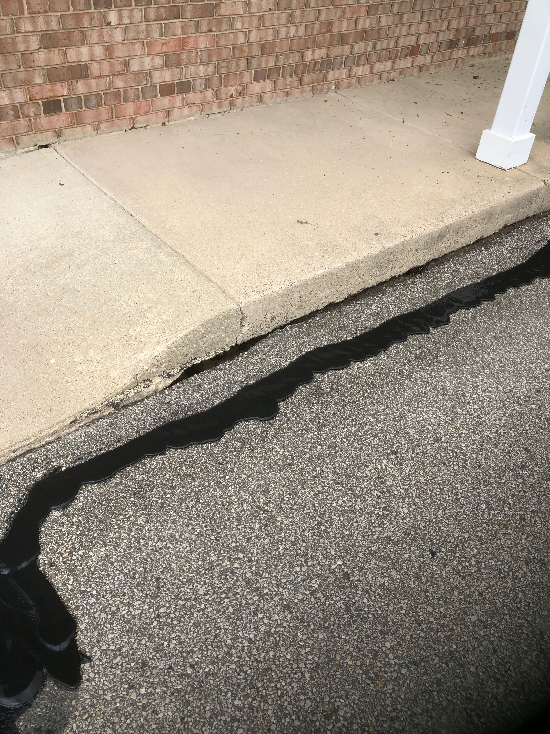 A person is standing on a sidewalk next to a brick wall.