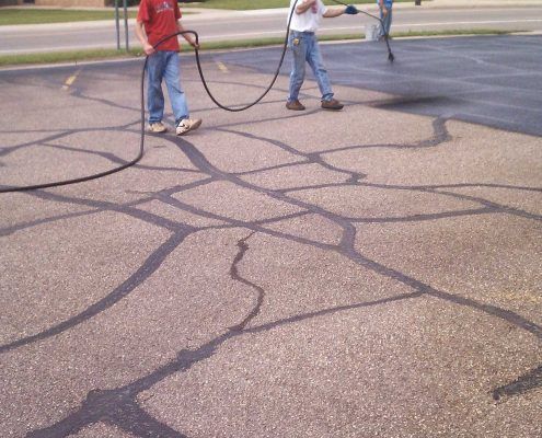 A couple of people standing on a concrete surface with a hose A couple of people standing on a concrete surface with a hose