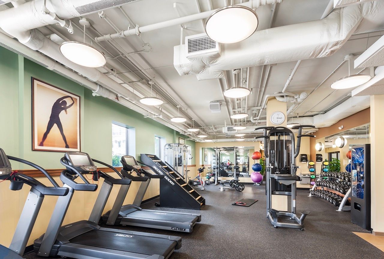Indoor fitness center with treadmills, a multi-gym, free weights, and bright overhead lights.