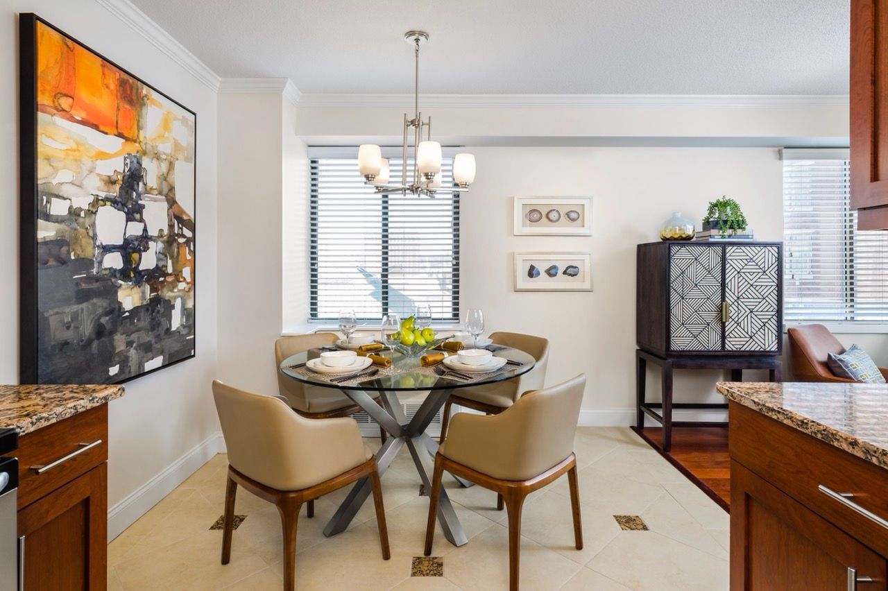 Dining area in a modern apartment with a round glass table and beige chairs.