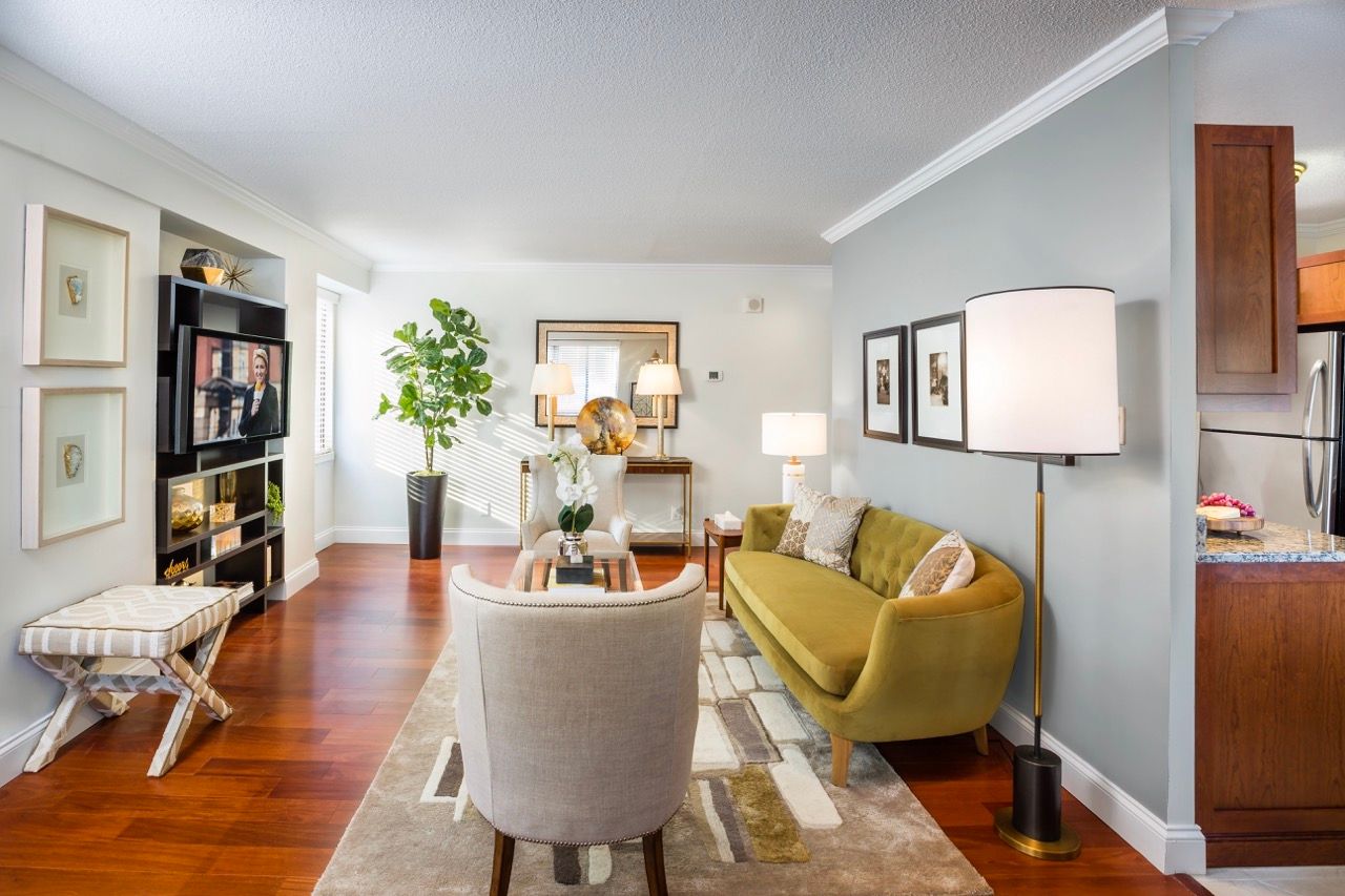 Living room in a modern apartment with hardwood floors, mustard sofa, and contemporary decor.