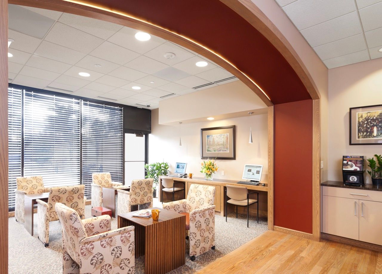 Interior community lounge with curved archway, patterned chairs, and computer stations.