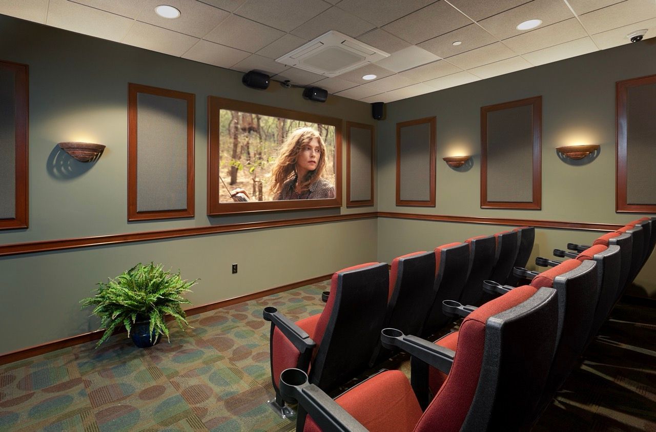 Indoor community theater room with red upholstered seats and wall panels.