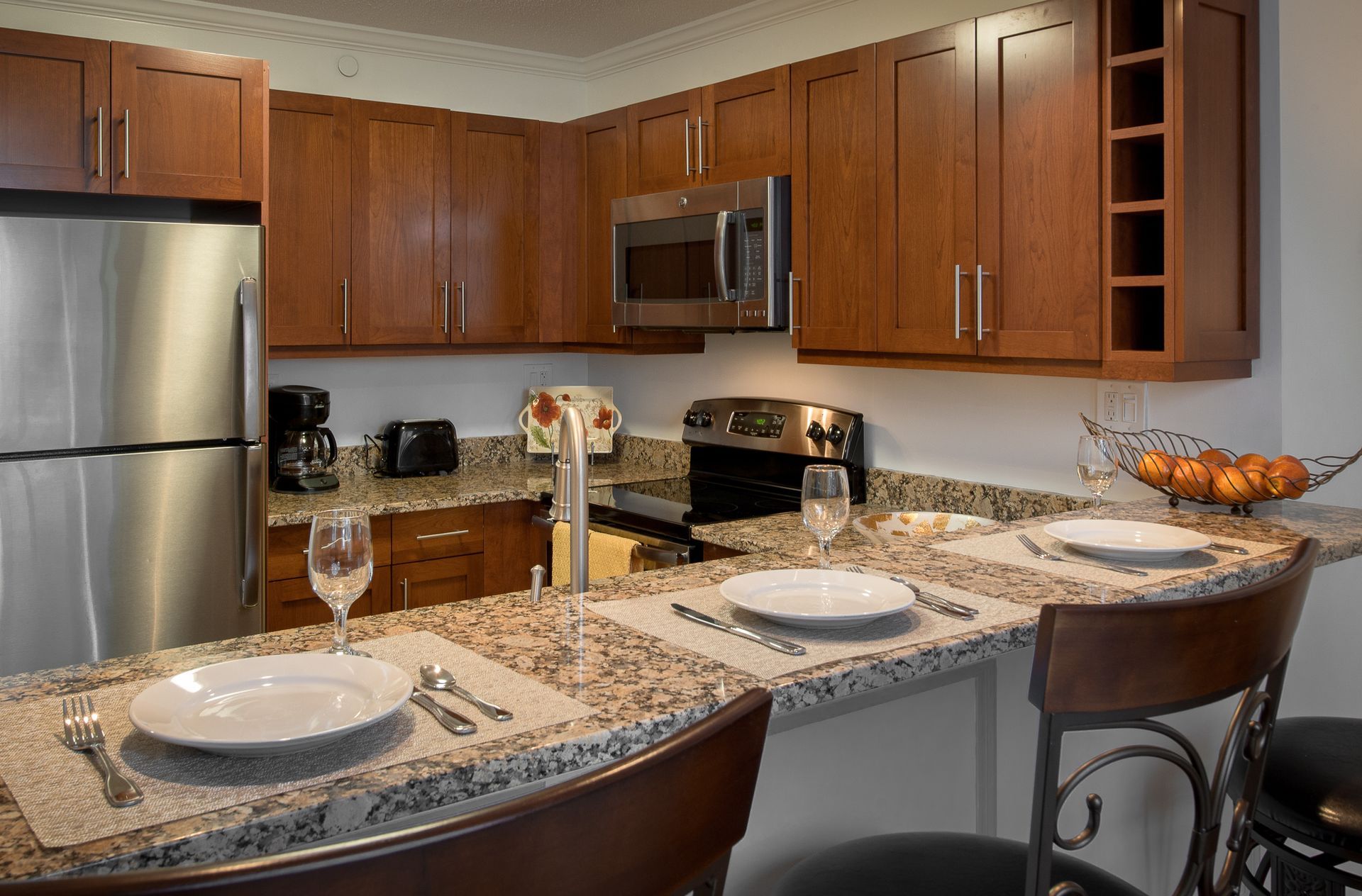 Apartment kitchen with granite countertops, wooden cabinets, and stainless appliances.