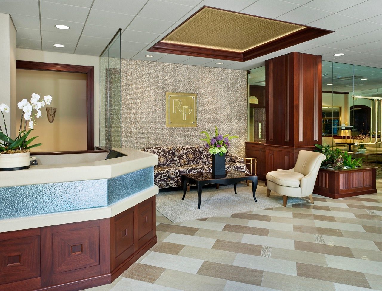 Modern apartment lobby with reception desk, seating, and mosaic wall.